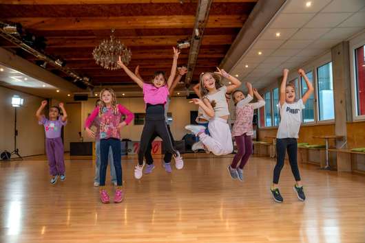 Eine Gruppe von Kindern springt fröhlich während eines Hip-Hop-Tanzkurses in die Luft