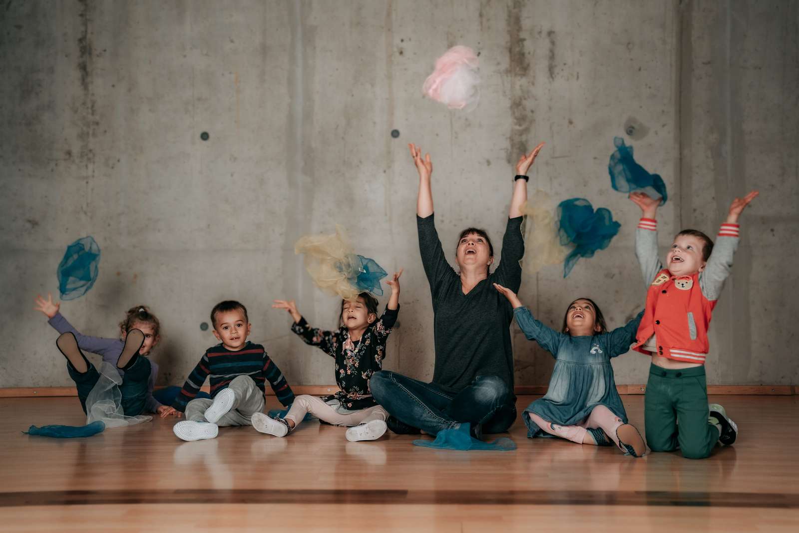 Eine Tanzlehrerin und eine Gruppe von Kindern spielen fröhlich mit bunten Tüchern in einem Kindertanzkurs Kindertanzkurs – Spiel & Spaß bei Tanzschule No.10